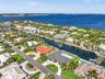 Aerial perspective of a coastal neighborhood featuring deep-water canal access, private boat docks, residential swimming pools, mature palm landscapin