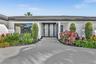 Contemporary exterior featuring a textured concrete driveway, dual glass entry doors with dark frames, and manicured landscaping
