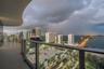Curved balcony with large-format tile flooring and a glass-paneled railing overlooking an urban skyline and waterfront