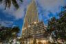High-rise residential tower featuring a curvilinear architectural facade, extensive exterior balconies, glass curtain walls, and integrated ground-lev
