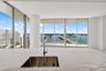 Kitchen featuring a waterfall-edge stone countertop, undermount stainless steel sink, chrome faucet, floor-to-ceiling windows, and access to a balcony