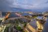 High-altitude perspective featuring expansive water frontage, illuminated bridges, urban infrastructure, and coastal skyline scenery