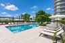 Outdoor swimming pool featuring a tile deck, integrated landscaping, and shaded areas