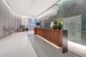 Reception area featuring a wood-panel console, large-format green stone wall cladding, custom crystal-style pendant lighting, polished white flooring,