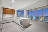 Contemporary kitchen featuring custom white flat-panel cabinetry, wood-finish upper cabinets, stone-surfaced island with integrated wine refrigeration