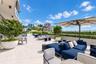 Expansive rooftop terrace featuring large-format stone-finish flooring, integrated perimeter landscaping, and elevated masonry wall enclosures