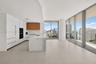Kitchen featuring floor-to-ceiling cabinetry, a stone-surface island with waterfall edge, integrated appliances, wood-finish upper cabinets, and expan