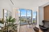 Floor-to-ceiling glass windows, wood-finish flooring, recessed lighting, and a private balcony featuring a metal railing