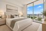 Floor-to-ceiling windows featuring panoramic urban scenery and a private balcony with glass railing