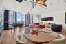 Living area featuring floor-to-ceiling windows, wood-finish flooring, custom geometric overhead lighting, and built-in wall-mounted cabinetry