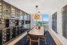 Custom floor-to-ceiling glass-front wine cabinetry, expansive floor-to-ceiling windows, spherical multi-bulb pendant lighting, and light-toned wood-fi