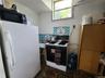 Kitchen featuring freestanding refrigerator, black range with gas cooktop, decorative backsplash, and dark stone finish floors