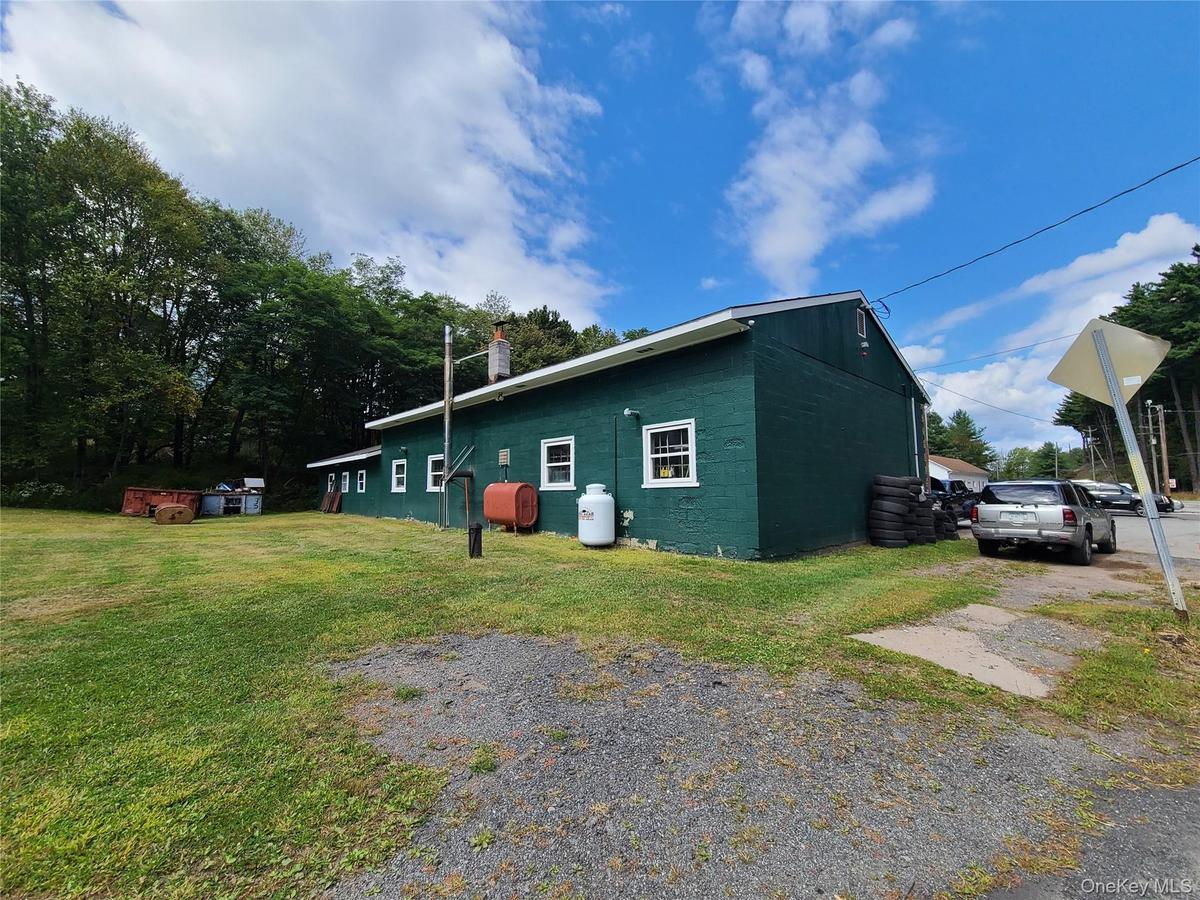 View of property exterior featuring concrete block siding, heating fuel, a lawn, and a chimney