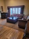 Hardwood flooring, built-in bar, expansive window with horizontal blinds, and a decorative window valance