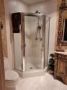 Tiled flooring with a corner shower enclosure featuring a glass door and chrome trim