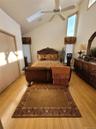 Vaulted ceiling with skylight, wood-finish flooring, two window treatments, and a ceiling fan with light