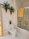 White tile flooring with a matching toilet, a built-in shower-tub combination, and a glass shower enclosure