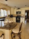 Kitchen featuring extensive cream cabinetry, dark countertops, built-in microwave, under-sink window, and tile flooring