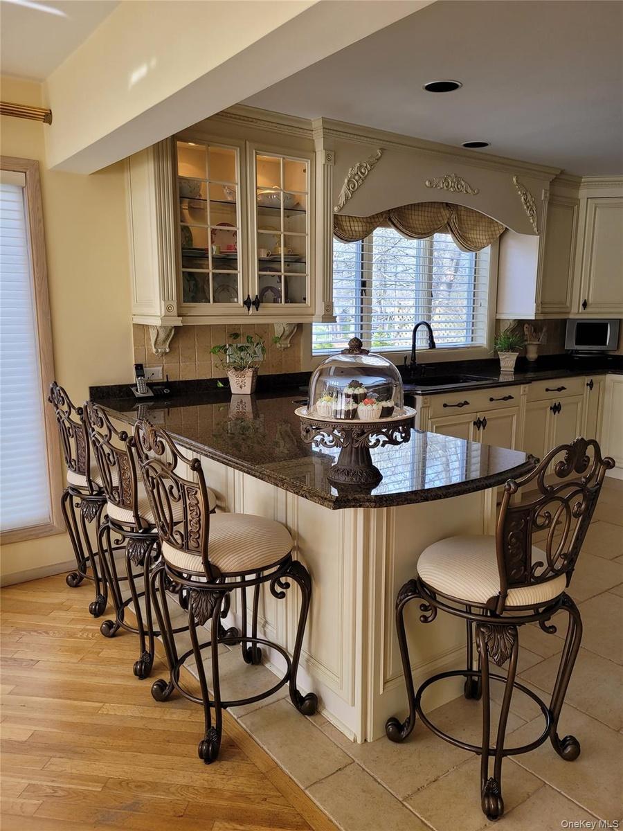Kitchen island with a granite countertop, paneled base, and integrated seating