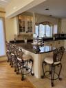 Kitchen island with a granite countertop, paneled base, and integrated seating