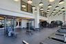 High-ceiling fitness area featuring extensive equipment, recessed lighting, and large windows