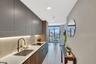 Galley kitchen featuring flat-panel cabinetry, integrated under-cabinet lighting, a built-in cooktop, and a stainless steel sink with a bronze-tone fa