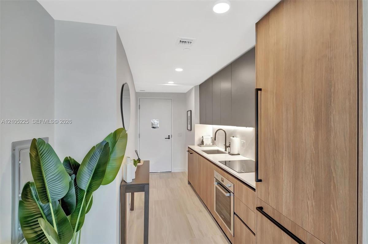 Integrated kitchen with wood-finish cabinetry, solid surface countertops, and stainless steel appliances