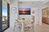 Floor-to-ceiling glass sliding door, light-toned tile flooring, and a bathroom vanity featuring a neutral-toned cabinet and modern faucet