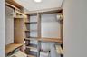 Walk-in closet featuring custom wood-finish built-in shelving, multiple hanging rods, and integrated overhead storage