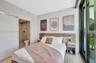 Light wood-finish flooring, built-in headboard with integrated lighting, attached nightstands, and a full-height sliding glass door