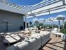 Expansive rooftop deck featuring a louvered pergola, wood-finish flooring, and a panoramic skyline backdrop
