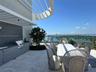 Expansive outdoor terrace featuring a built-in grill station, tile flooring, and a glass perimeter