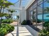 Expansive outdoor terrace featuring mature palm trees, lush landscaping, and a slatted pergola