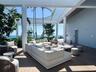 Expansive outdoor terrace featuring slatted wood-finish flooring, a white pergola structure, and mature perimeter landscaping
