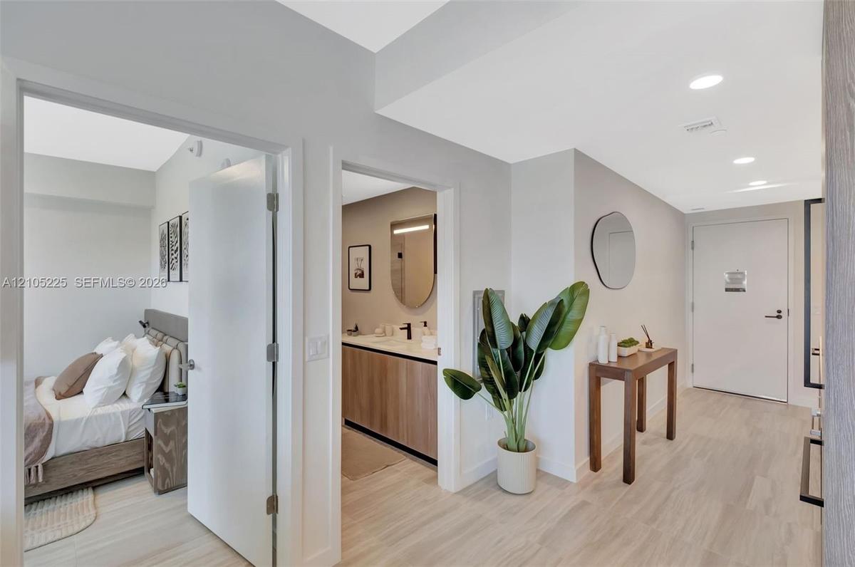 Recessed ceiling lighting, wood-finish flooring, white walls, and a contemporary bathroom vanity with a rectangular mirror
