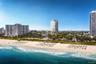 Coastal property featuring an expansive sandy beach, mature palm trees, and direct oceanfront access