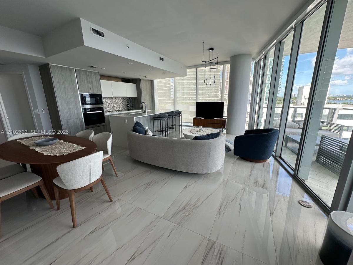 Open-concept kitchen featuring integrated cabinetry, stainless steel built-in oven, quartz island, and polished stone-finish flooring throughout