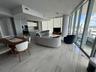 Open-concept kitchen featuring integrated cabinetry, stainless steel built-in oven, quartz island, and polished stone-finish flooring throughout