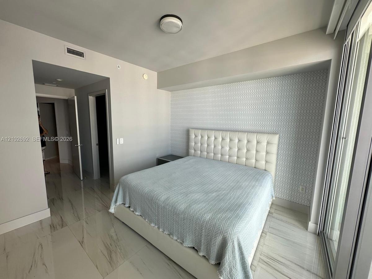 Large-format stone-finish flooring and geometric patterned accent wall featuring a recessed alcove