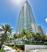 High-rise structure featuring floor-to-ceiling glass paneling, extensive wraparound balcony tiers, and contemporary glass railing systems, set against