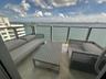 Private balcony featuring herringbone-patterned tile flooring and a glass-paneled railing overlooking the water