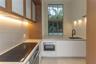 Kitchen featuring custom wood-toned cabinetry with glass-paneled upper doors, stone countertops, a flat-surface induction cooktop, integrated stainles