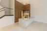 Kitchen featuring full-height wood-finish cabinetry, waterfall-edge stone countertop, undermount sink with matte black faucet, and glass staircase rai