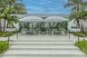 Outdoor terrace featuring oversized light-colored tiling, a tiered staircase with metal handrails, a climbing vine wall, and perimeter tropical landsc