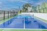 Rooftop pickleball court featuring a high-contrast blue and green acrylic surface, integrated netting, perimeter metal fencing, and decorative wall mu