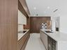 Modern kitchen featuring custom wood-finish cabinetry, stone-surface countertops, a large center island with integrated wine refrigeration, and stainl