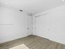 Neutral-toned wood-finish tile flooring, recessed ceiling lighting, and sliding closet doors with matte black hardware