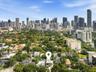 Aerial perspective showcasing a multi-story residence with a flat roofline and a swimming pool, set within a residential area featuring mature trees a