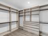Walk-in closet featuring extensive built-in shelving, integrated hanging rods, a stack of custom storage drawers, and wood-finish flooring
