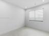 Neutral-toned interior space featuring large-format tile flooring, recessed lighting, and a window equipped with striped roller shades